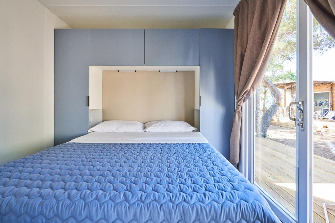 Sypialnia z podwójnym łóżkiem i wbudowaną szafą, widok na taras.