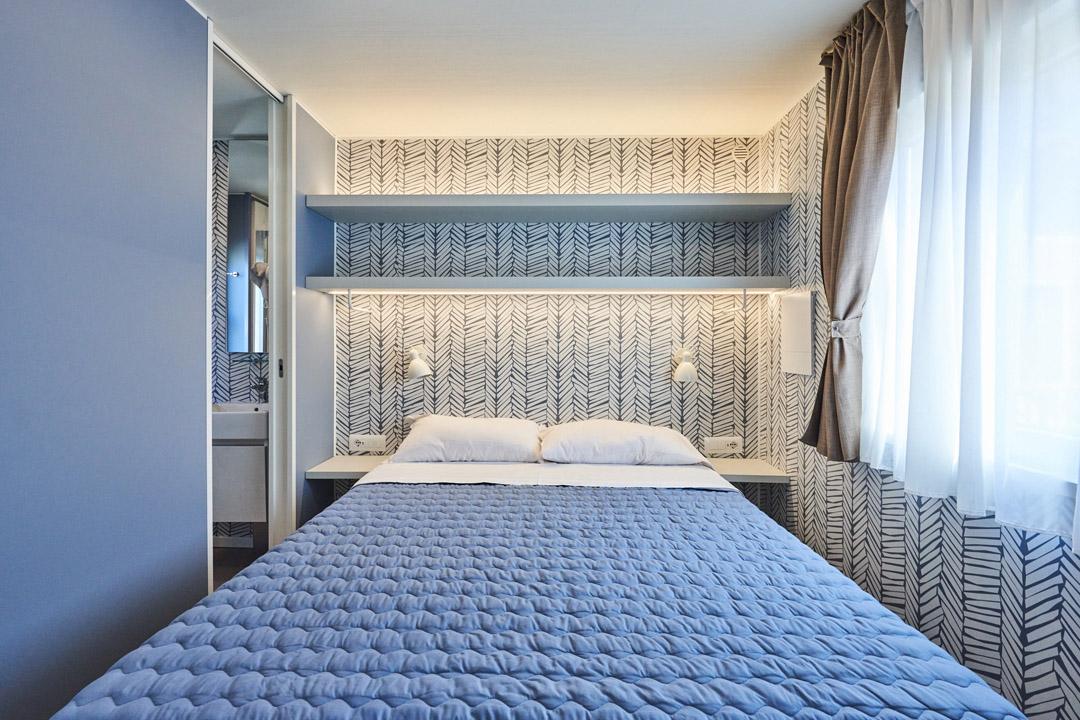 Moderne slaapkamer met tweepersoonsbed en geometrische decoratie.