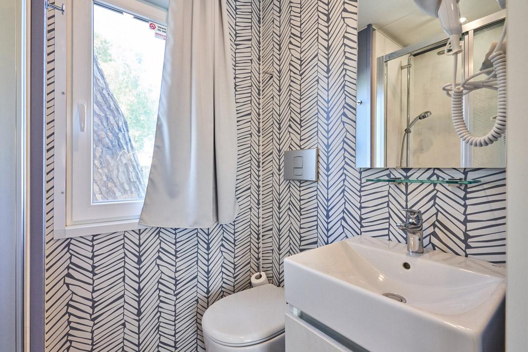 Modern bathroom with geometric wallpaper and bright window.