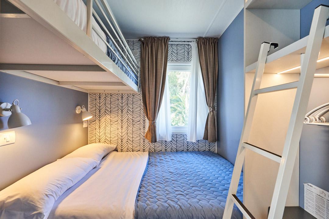 Slaapkamer met stapelbed en raam, versierd in blauwtinten.
