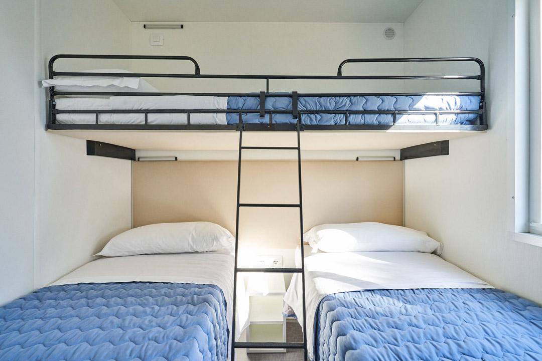 Room with bunk bed and two single beds.